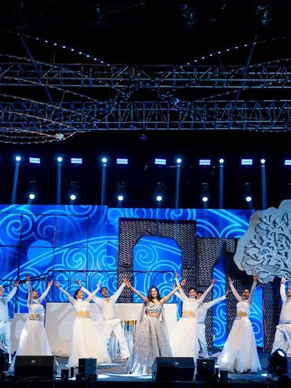 A performance featuring the bride with backup dancers. The choreography is designed to highlight the bride while the synchronized movements and props, like the large tree cutout, create a visually rich and cohesive stage picture.