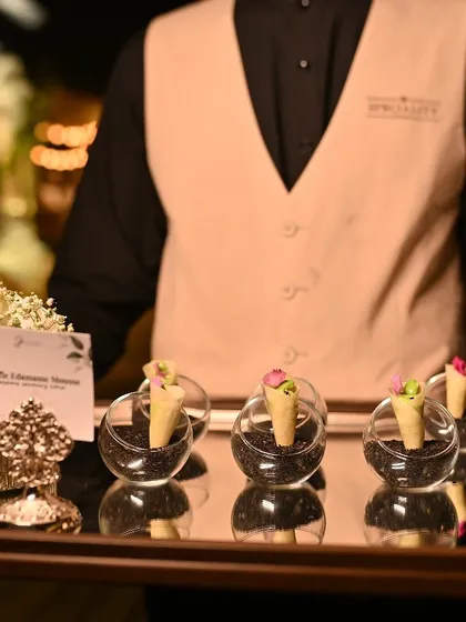 A member of our service team, dressed impeccably, presenting a tray of our Truffle Edamame Mousse cones. This is the effortless precision we bring to every event.