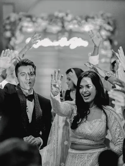 The energy is electric as the couple makes their grand entrance, cheered on by their closest friends. This black and white shot freezes a moment of pure, unadulterated joy and celebration, showing the fun side of your big day.