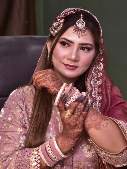 The bride admiring her henna-adorned hands, looking thoughtful and beautiful.