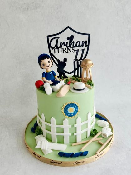 A cricket-themed cake for Arihan's 11th birthday, with a fondant figurine, a picket fence, and cricket equipment.