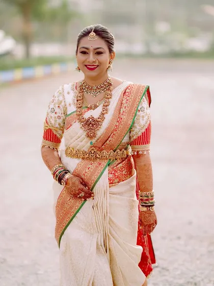 This bride is ready for her wedding ceremony in a classic off-white and red silk saree. I designed the puff-sleeve blouse with traditional motifs to add a vintage and elegant touch to her ensemble.