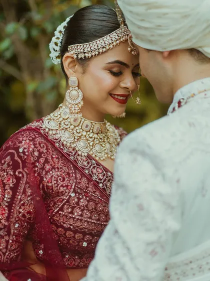 A romantic close-up of the bride and groom. Her classic red lip and soft, glowing makeup create a timeless look that is perfect for these intimate moments.