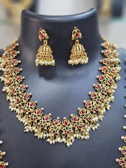 A detailed view of the matching jhumkas and the intricate floral design of the necklace.