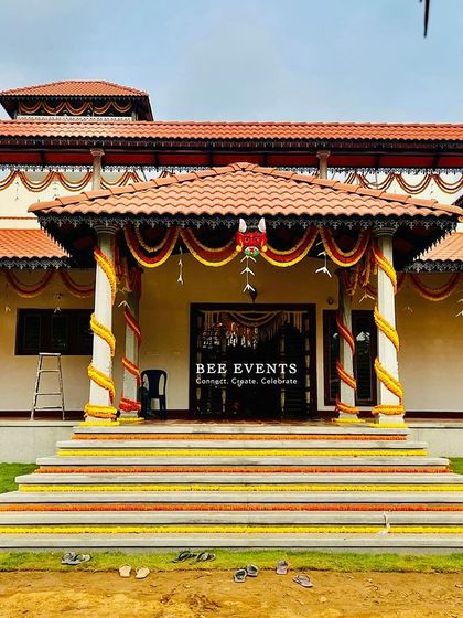 A frontal view of the beautifully decorated traditional farmhouse. The steps are lined with flowers, and the pillars are wrapped in garlands, creating a grand and welcoming entrance.