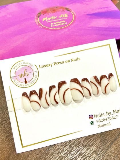 A chic and modern press-on set featuring a white base with brown swirl designs. This is a great example of a minimalist yet eye-catching look.