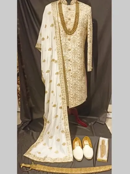 The complete groom's package available for rent: an ivory sherwani, matching shoes (juttis), and a traditional sword (talwar).
