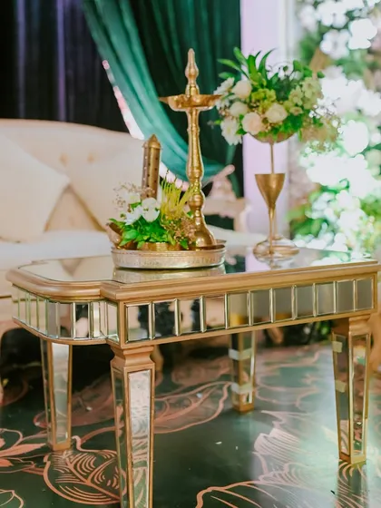 A mirrored table reflects the surrounding decor, holding a traditional brass lamp and other curated objects that add a touch of Indian heritage to the modern luxury setting.