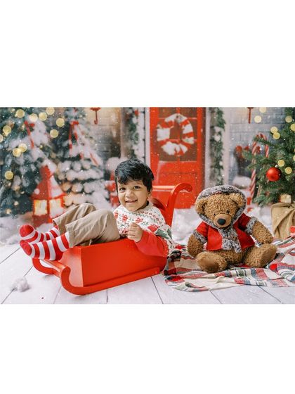 A little boy in a red sleigh, looking happy and festive. A perfect photo for a Christmas card.