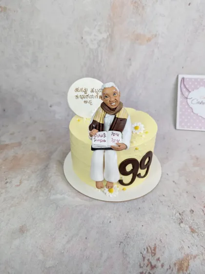 A full view of the 99th birthday cake. The simple daisy accents complement the yellow buttercream and the detailed figurine.
