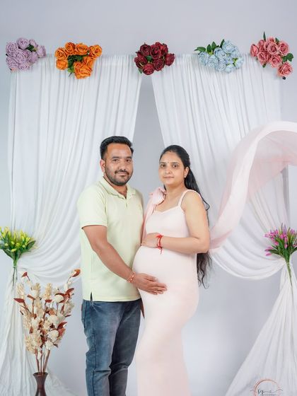 A classic portrait of the expecting couple. The mom-to-be is radiant in a soft pink gown, with her partner by her side, creating a timeless memory.
