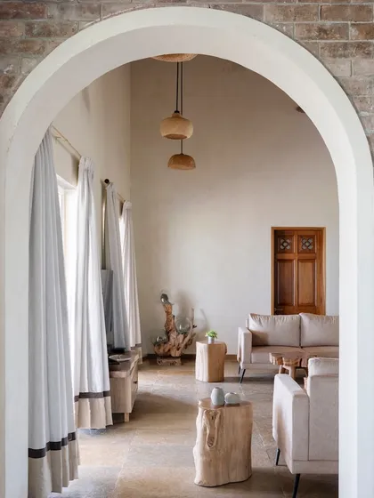 A view from the exterior brick wall into the living space, showing how the design seamlessly connects different areas of the home through consistent materials and arched openings.