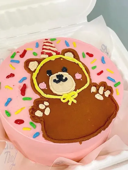 A cute and playful caricature bento cake with a party bear. These hand-drawn designs add a unique and personal touch to any celebration.