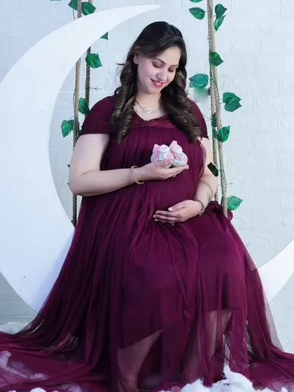 Our moon swing prop surrounded by fluffy clouds makes for a dreamy photo. The deep maroon gown drapes beautifully, adding to the celestial, whimsical feel of the portrait.