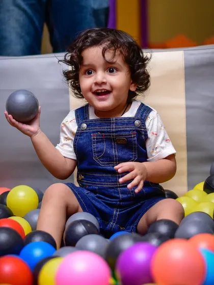 The simple joy of holding a ball in a pit full of colors. A perfect moment for a toddler.