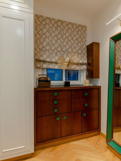The green-framed mirror and matching drawer knobs create a point of emphasis in this dressing area, tying the custom furniture pieces together.
