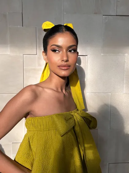Sunkissed, glowy, and cutesy. This look features a sharp half-eyeliner and a high ponytail with a bright yellow bow, perfect for a fun daytime event.