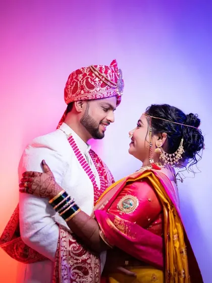 A loving gaze between the newly married couple, with vibrant background lighting that adds a modern touch to their traditional look.