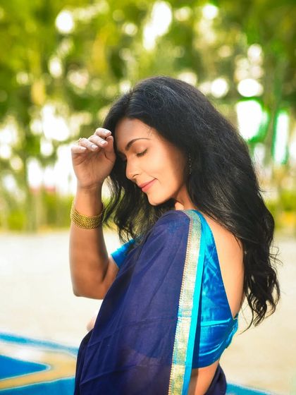 A soft and serene portrait of a woman in a blue saree, captured outdoors with beautiful natural light.