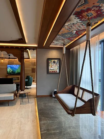 A standout feature in the Embassy Lake Terraces apartment is this traditional Indian oonjal, or swing. We suspended it by the window, creating a perfect spot for relaxation with a view. The ceiling panel above features a vibrant textile pattern, adding a unique decorative touch.