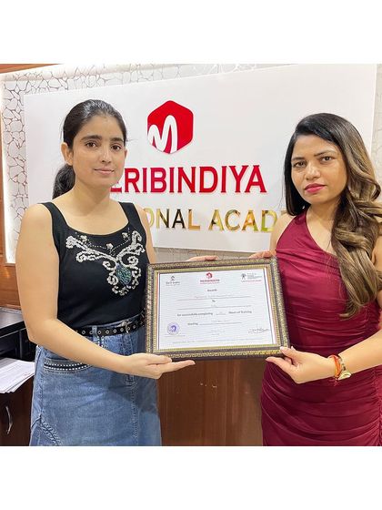 A proud graduate of Meribindiya International Academy, holding the proof of her professional training.