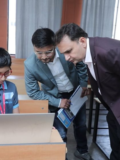 Our founder and a judge look on as a student works on his coding project. This image highlights our focus on preparing students for top universities and scholarships by building a strong portfolio of tech skills.