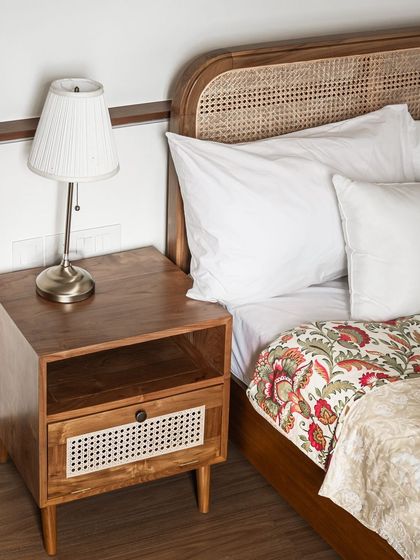 Another view of the teak and rattan bed and side table in a client's home. The combination of materials adds texture and warmth, creating a sophisticated yet comfortable bedroom environment.