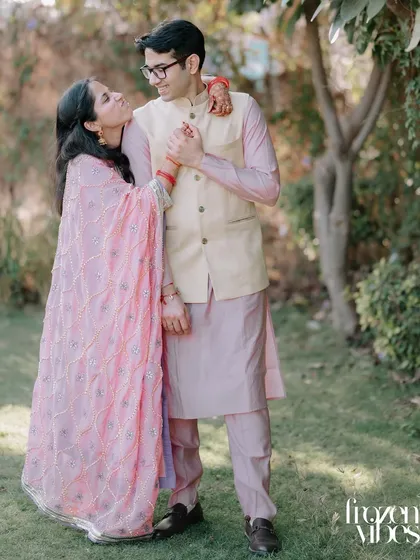 A full-length portrait of Kanika and Abhinav in a garden. Their pastel outfits and the soft lighting create a light and airy feel.