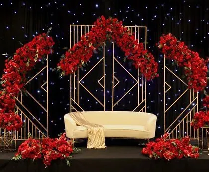 For a bold and dramatic Sangeet, I designed this stage with a geometric gold frame and a profusion of red roses. The starry black backdrop makes the red and gold elements stand out powerfully.