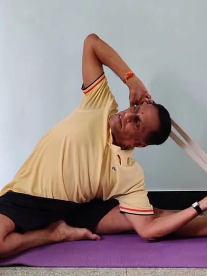 The final stage of Parivrtta Janu Shirshasana with a belt, where the head comes towards the knee and the chest is revolved upwards.