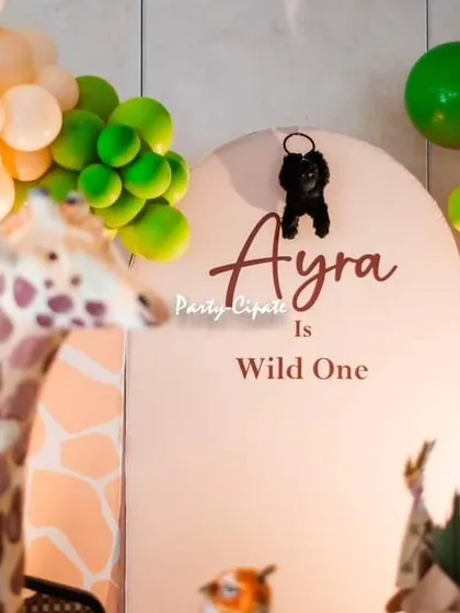 The backdrop for this safari party featured a subtle giraffe print and a little gorilla prop playfully hanging over the birthday girl's name.