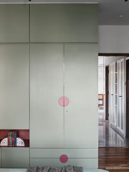 The wardrobe in the kids' room features clean lines and pops of color with magenta circle handles, providing a fun and functional storage solution.