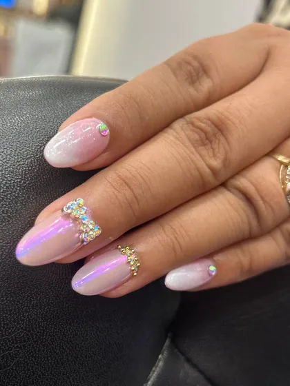 A close-up of the iridescent ombre nail with a hand-placed rhinestone bow. This shows the precision required to create these delicate embellishments that make the design so special.