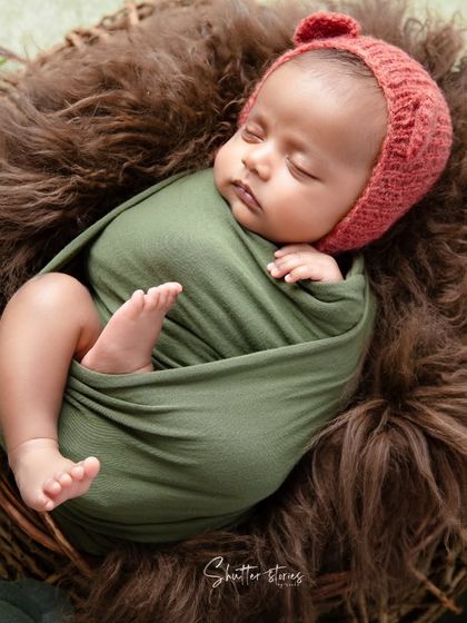 This shot shows the full 'tucked' pose within the basket, a classic and safe way to pose a newborn.