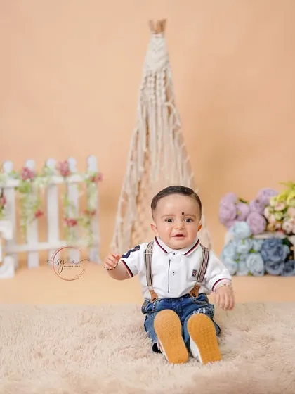A wide shot showing the full setup with a "ONE" sign, a white picket fence, and a macrame teepee, creating a charming rustic scene.