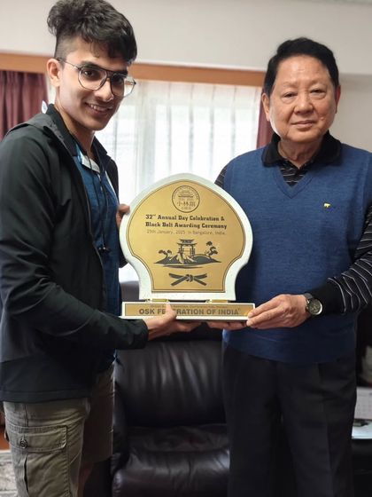 A senior student presents a plaque to Hanshi Minoru Nakazato at his home dojo in Okinawa, bridging our communities.