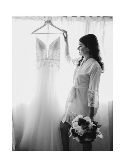 A beautiful black and white silhouette of the bride with her wedding dress. The backlighting from the window creates a soft and artistic getting-ready portrait.