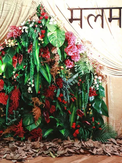 A mountain of tropical leaves and red flowers creates a dramatic and lush photo backdrop for a Diwali collection launch.