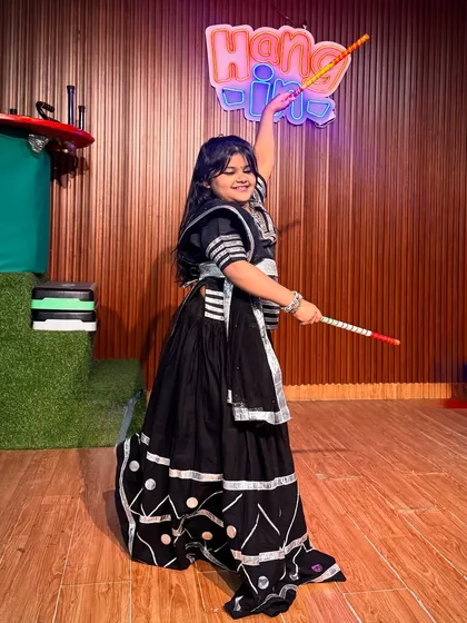 This young dancer strikes a perfect pose, showcasing her beautiful black and silver ghagra choli. Her smile and confident stance capture the true spirit of our Garba classes.