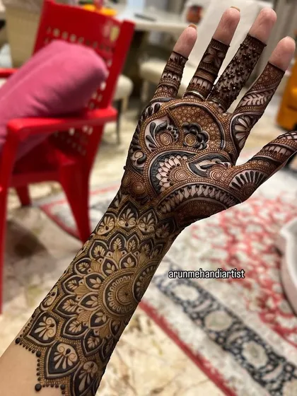 A close-up of a single hand adorned with a full mandala and paisley design. This view highlights the precision of the line work and the richness of the henna paste.