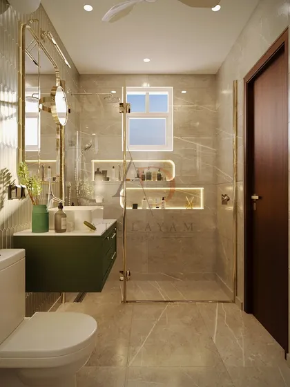This bathroom design maximizes a compact space with a rich green vanity, gold-accented hardware, and a glass shower partition to maintain an open feel.