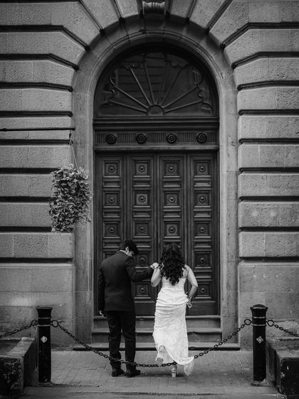 A black and white shot of the couple from behind as they approach a grand door, creating a sense of story and anticipation.