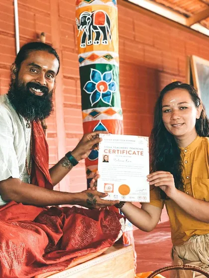 A graduating student receives her certificate with a proud smile. Each graduate becomes part of our global Soham Yoga family, ready to share the light of yoga with the world.