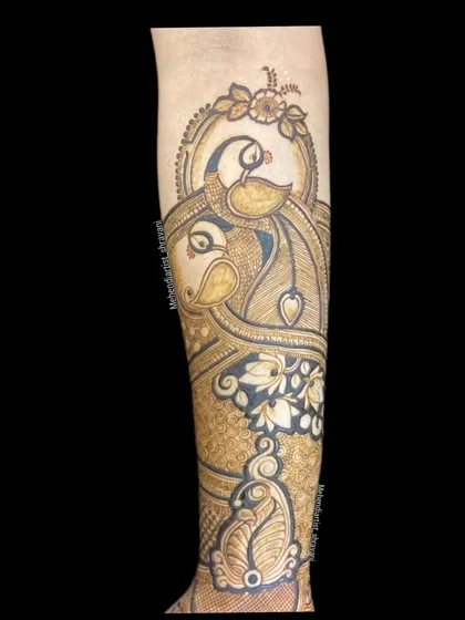 A close-up of a single forearm with a large, stylized fish motif. This is a symbol of good fortune and is surrounded by delicate floral and leaf patterns.