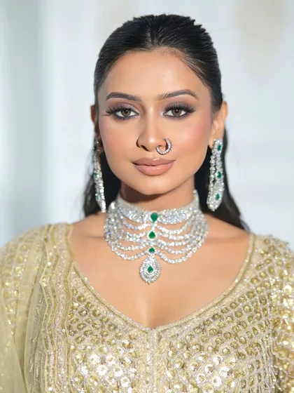 A close-up of the all-gold sequin blouse, paired with a stunning diamond and emerald necklace. This shows how our outfits can be styled for a high-glamour event.