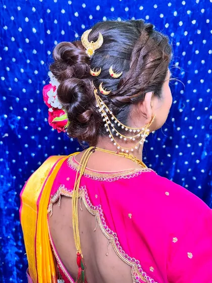 A detailed view of a stunning bridal bun, adorned with fresh flowers and traditional Maharashtrian hair accessories. The hairstyle is as important as the makeup.