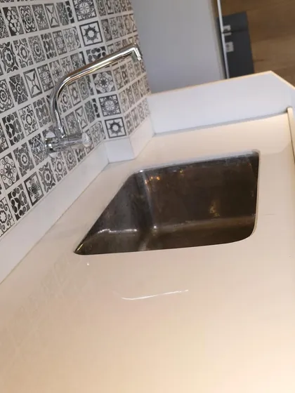 The details matter. This image shows a high-quality Corian countertop with an integrated sink, set against a classic black and white patterned tile dado, adding a touch of timeless charm.