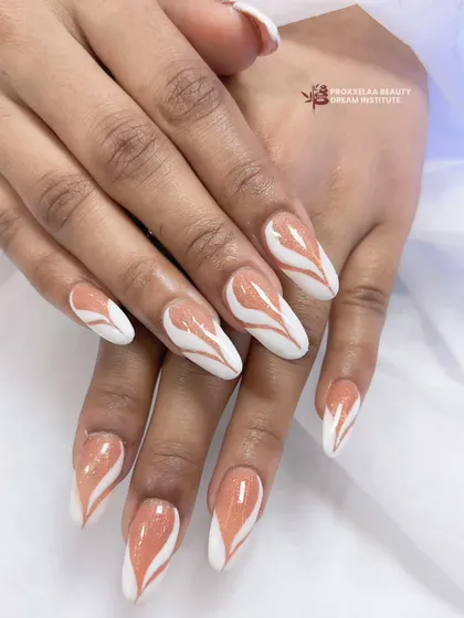 A clean and graphic design featuring a white base with heart-shaped negative space filled with a shimmery, neutral-toned polish on long stiletto nails.