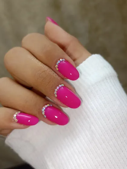 A simple yet glamorous design, with a bright magenta polish and a half-moon of sparkling crystals at the cuticle.