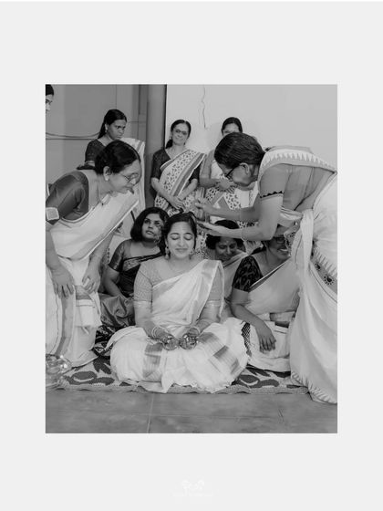 A black and white photo of the bride being blessed by the women in her family during a traditional ceremony.